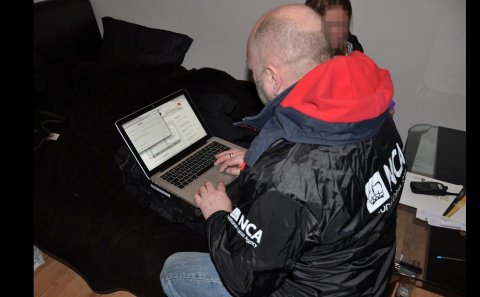 National Crime Agency Officer examining potential digital evidence after arrest and raid. Image: NCA 